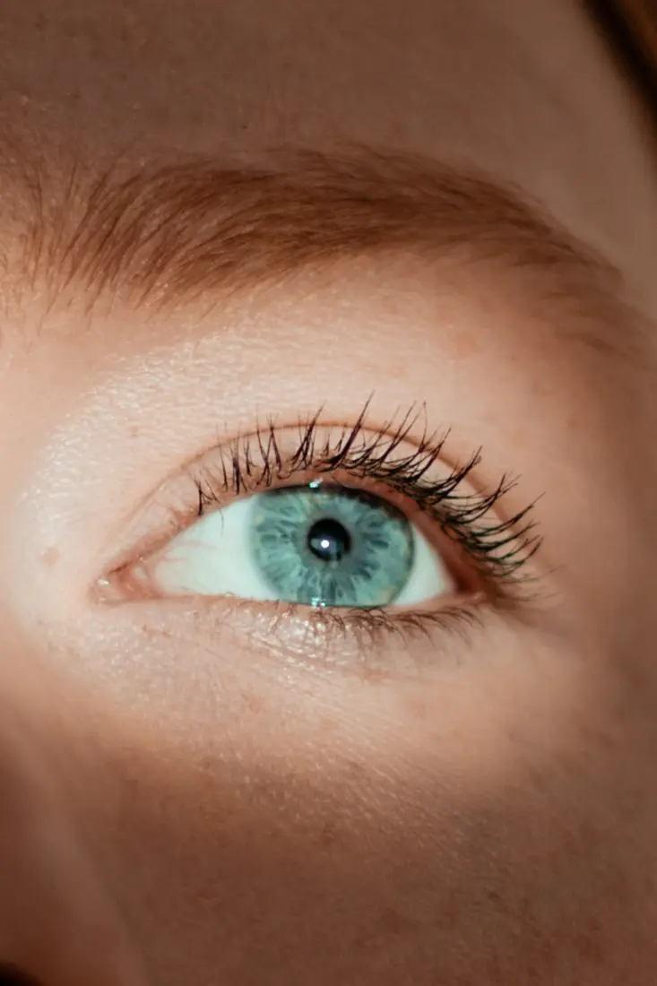 Close-up of a blue-green eye with natural curled lashes