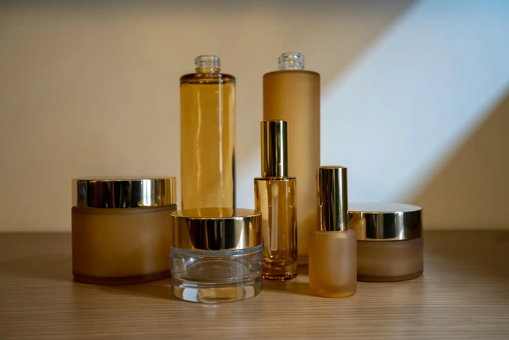 Amber glass skincare bottles and jars with gold lids on a shelf