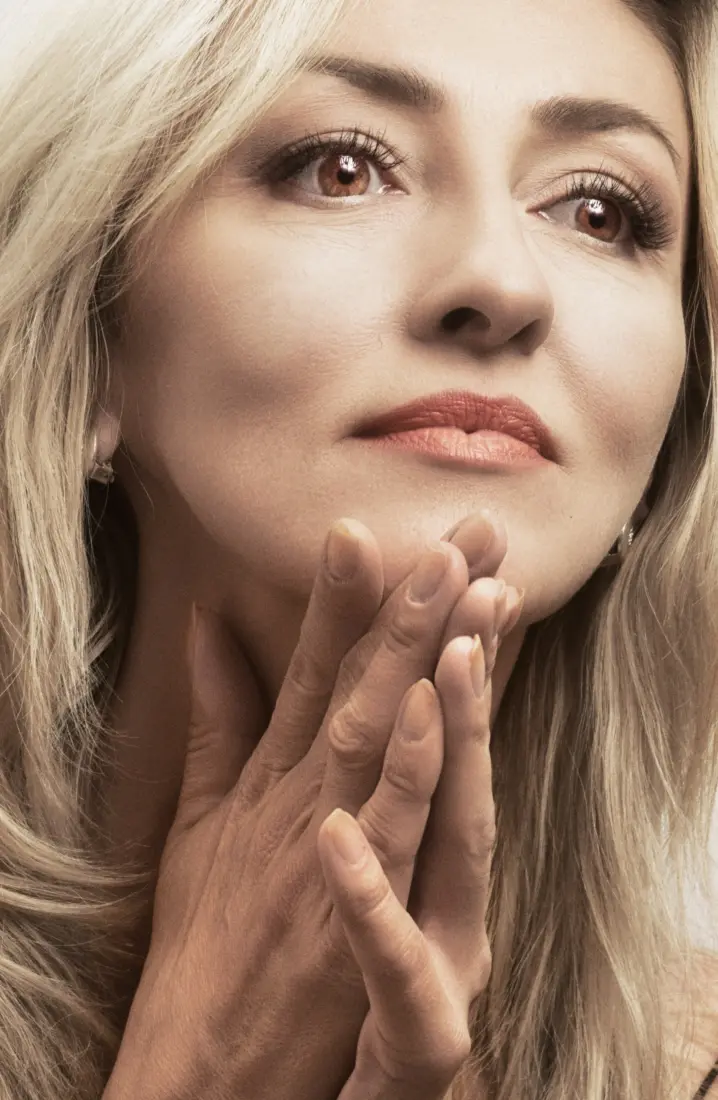Mature woman resting her fingertips against her chin and jaw